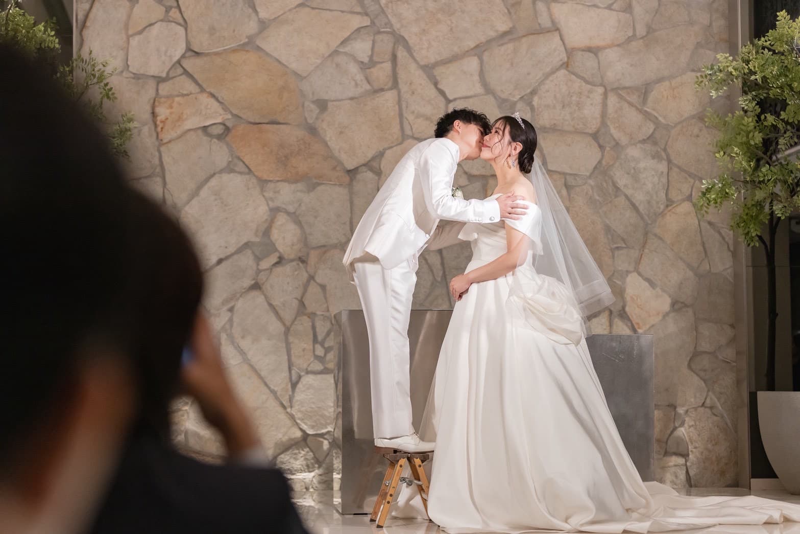 新郎新婦が踏み台を使って誓いのキスをしているシーン