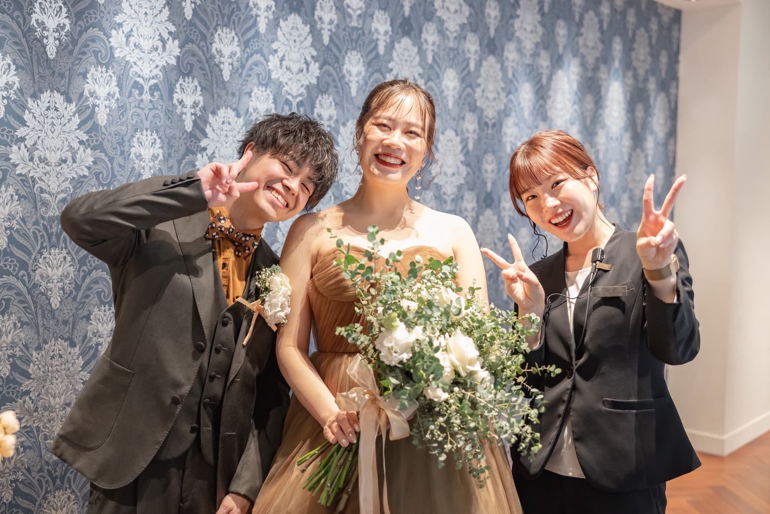 新郎新婦とウエディングプロデューサーの3人が笑顔で写っている写真